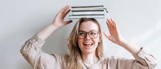 Junge Frau balanciert Bücher am Kopf. Headerbild zu den Besold Bücherabos.