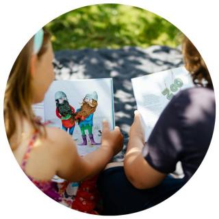 Kinder lesen im Freien. Link zu unserem Onlineschaufenster Kinderbücher für die Ferien.
